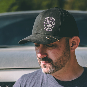 Paul Marier wearing a Black 'Hunt Fish Maniac' Logo Trucker Hat with a fish hook pin in it.