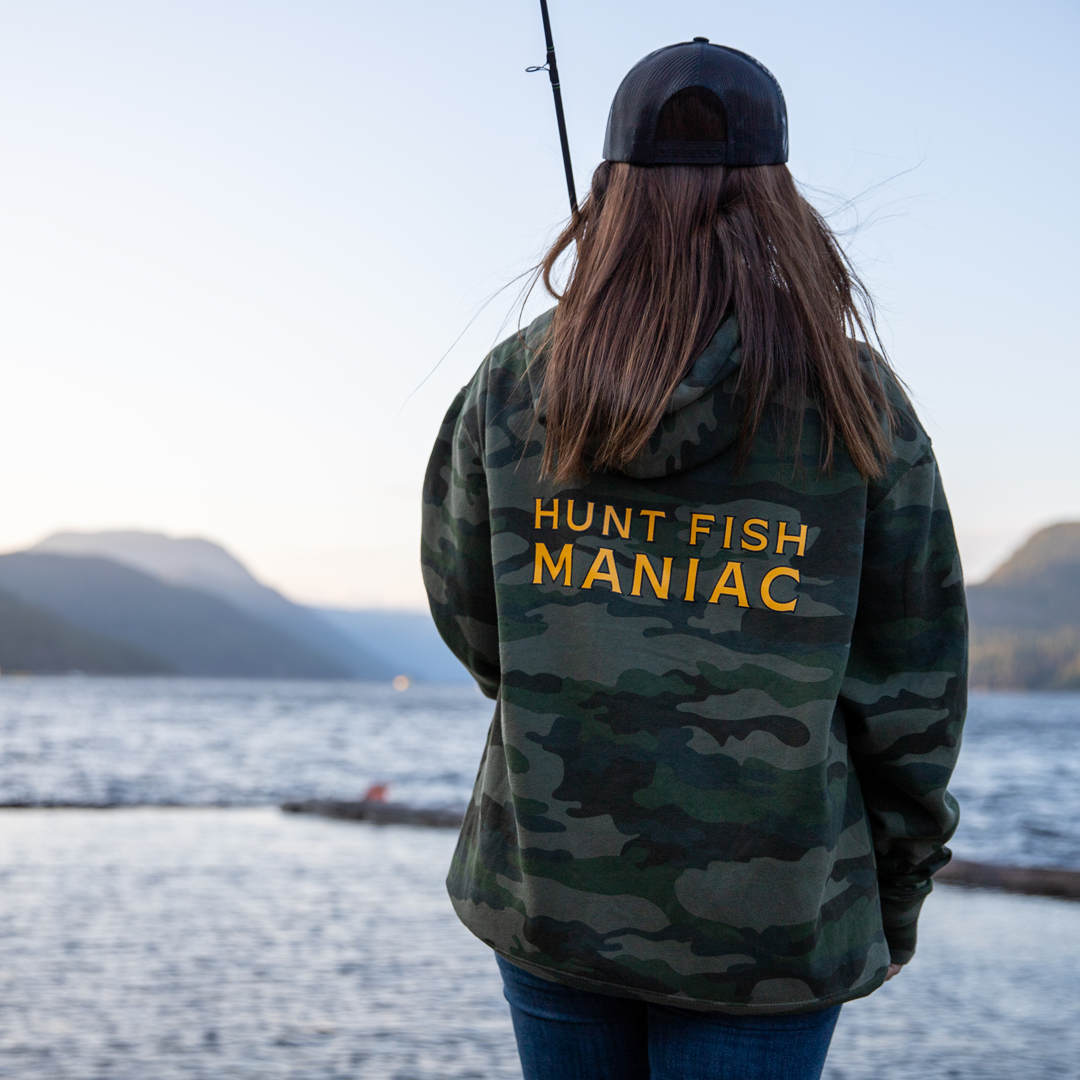 Woman fishing on the dock wearing a Camo 'Hunt Fish Maniac' Pullover Hooded Sweatshirt.