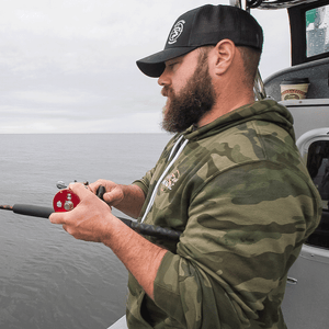 Man with a beard wearing Camo 'Hunt Fish Maniac' Pullover Hooded Sweatshirt while fishing on a boat.